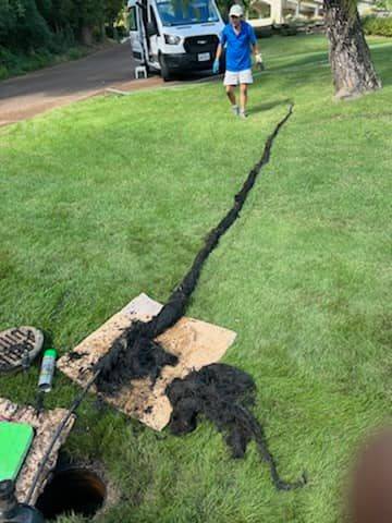 Excavated drain line trench cut across a lawn during a locating job