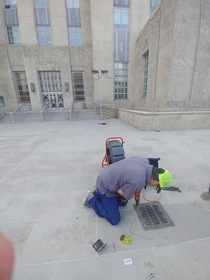 DrainCo technician servicing a drain grate outside a commercial building